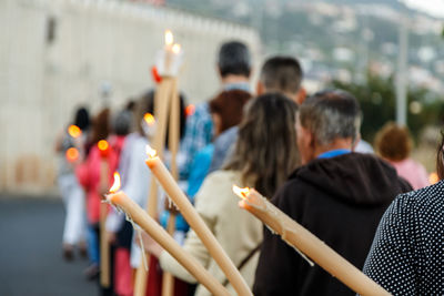 Back view of people in procession with candles in hand
