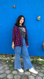 Portrait of woman standing against blue wall