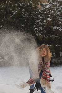 Blonde caucasian girl throws snow enjoying winter. happy joyful winter concept