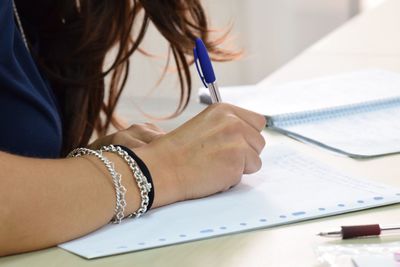 Cropped image of businesswoman writing in book at office