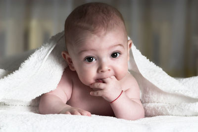 Portrait of cute baby boy lying on bed