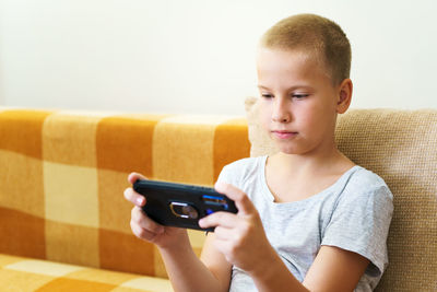 Close-up of cute little boy using smartphone looking at screen, curious child