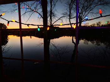 Reflection of silhouette trees on water at sunset