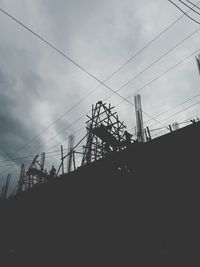 Low angle view of silhouette electricity pylon against sky