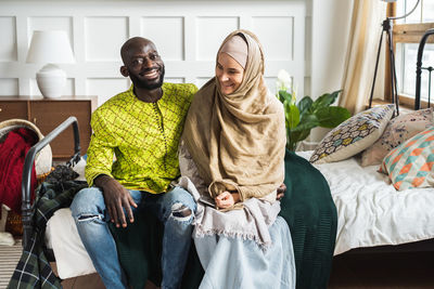 Smiling couple sitting on bed at home