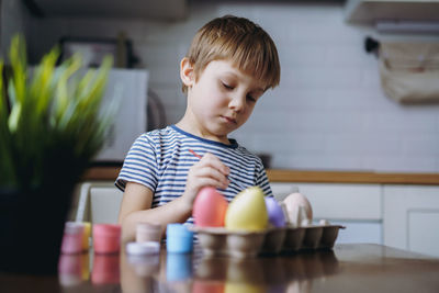 Cute little boy colouring eggs for easter