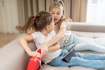 Girl and woman sitting on sofa at home