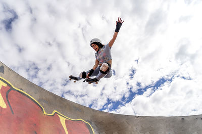 Woman with hand raised roller skating at skateboard park