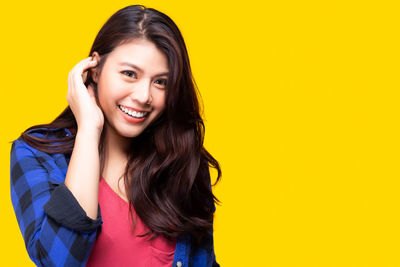 Portrait of a smiling young woman against yellow background