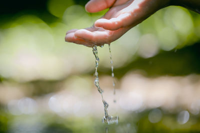 Close-up of hand falling water drops on person