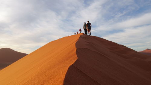 Rear view of people walking on desert against sky