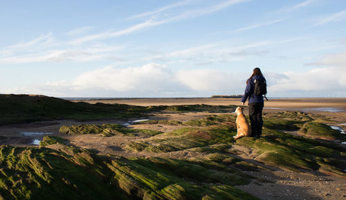 Rear view of man standing on landscape against sky