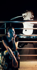 Young woman with arms outstretched standing outdoors at night