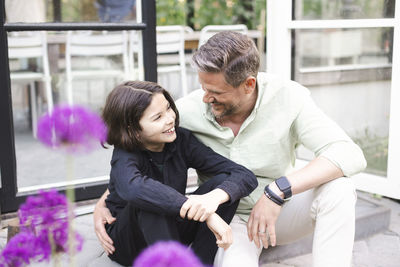 Happy father and son looking at each other while sitting together on steps