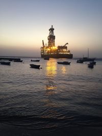 Boats in sea at sunset