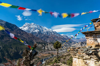 Multi colored flags hanging on mountain against sky