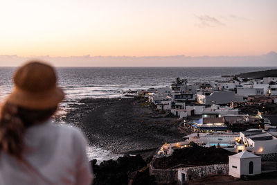 Rear view of woman looking at sea against sky during sunset