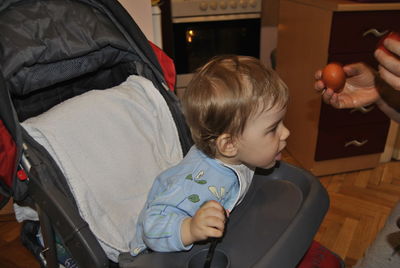 Cropped hands of showing eggs to son on baby stroller at home