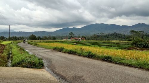 Road amidst field against sky