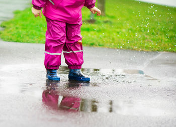 Low section of girl standing in puddle