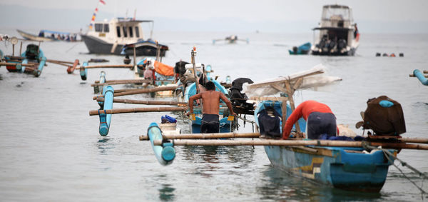 Rear view of fishermen in sea with outrigger fishing boats