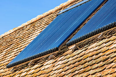 Low angle view of roof and building against blue sky