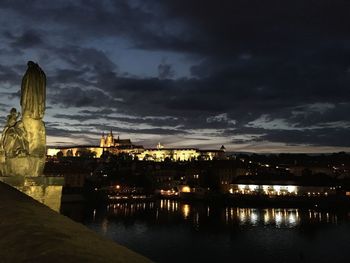 Illuminated buildings against cloudy sky