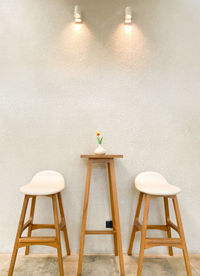 Empty chairs and table against wall