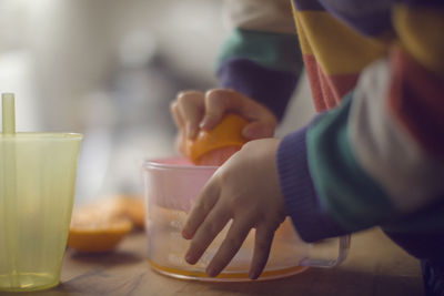 Midsection of kid making juice at home