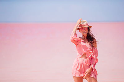 Woman standing on pink sea against sky