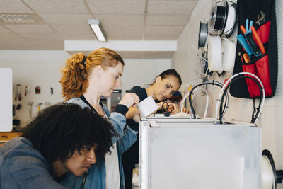 Multi-ethnic male and female engineers working on machinery at creative office