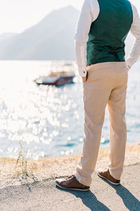 Low section of man standing at beach