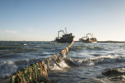 Dirty beach with shipwreck in the background at sunrise