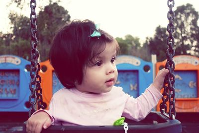 Portrait of cute boy sitting on swing at playground