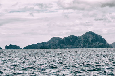 Scenic view of sea by mountains against sky