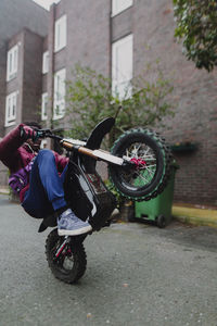 Man riding motorcycle on street against buildings in city