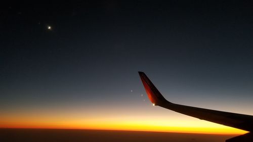 Airplane wing against sky at night