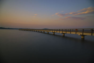 Pier over sea against sky during sunset