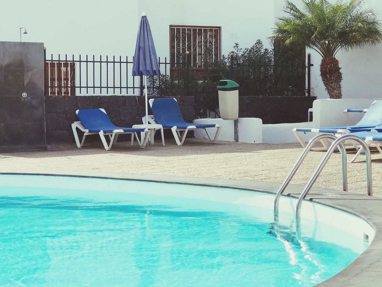 CHAIRS BY SWIMMING POOL AT BEACH AGAINST SKY