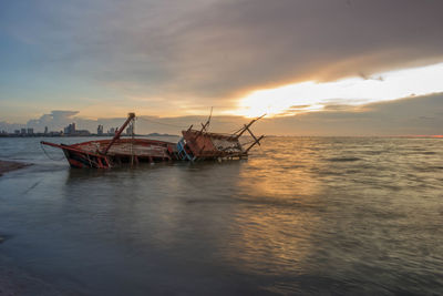 Fishing boat in sea against sky during sunset