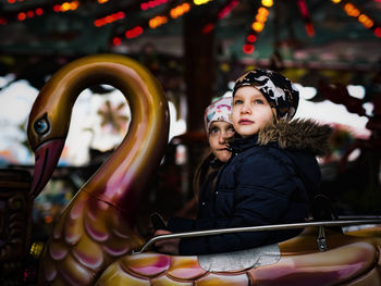 Girls looking away while sitting on amusement park ride