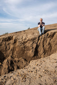 Rear view of man standing on rock against sky