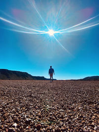 Rear view of woman walking on beach against sky