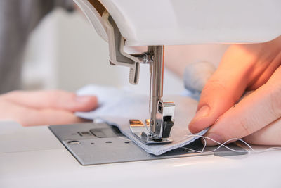 Cropped hand of tailor using sewing machine