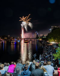 Firework display over river in city at night