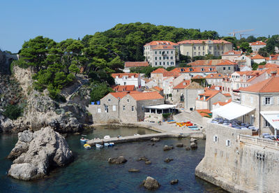 Houses by buildings in city against clear sky