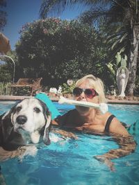 Portrait of young woman with dog swimming in pool