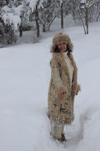 Portrait of cheerful woman standing on snow covered field