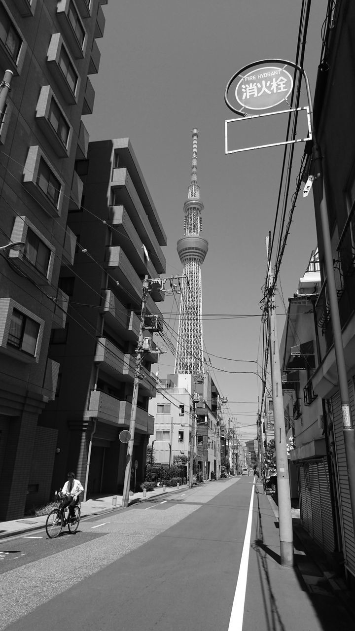 architecture, building exterior, built structure, city, tower, tall - high, street, clear sky, transportation, skyscraper, low angle view, residential building, building, communications tower, city life, modern, office building, the way forward, city street, outdoors, tall, sky, day, building story, diminishing perspective, spire, apartment