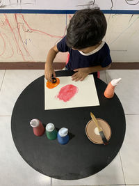 High angle view of boy painting while sitting at table